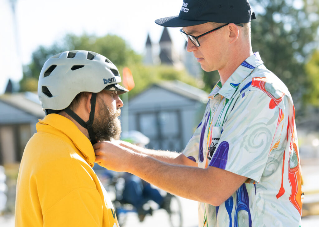A participant receives help adjusting a helmet strap during an adaptive cycling program