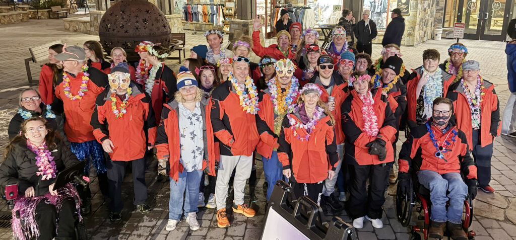 Team Powderhorn members wearing leis and festive accessories gather together during an evening event at Copper Mountain Resort.